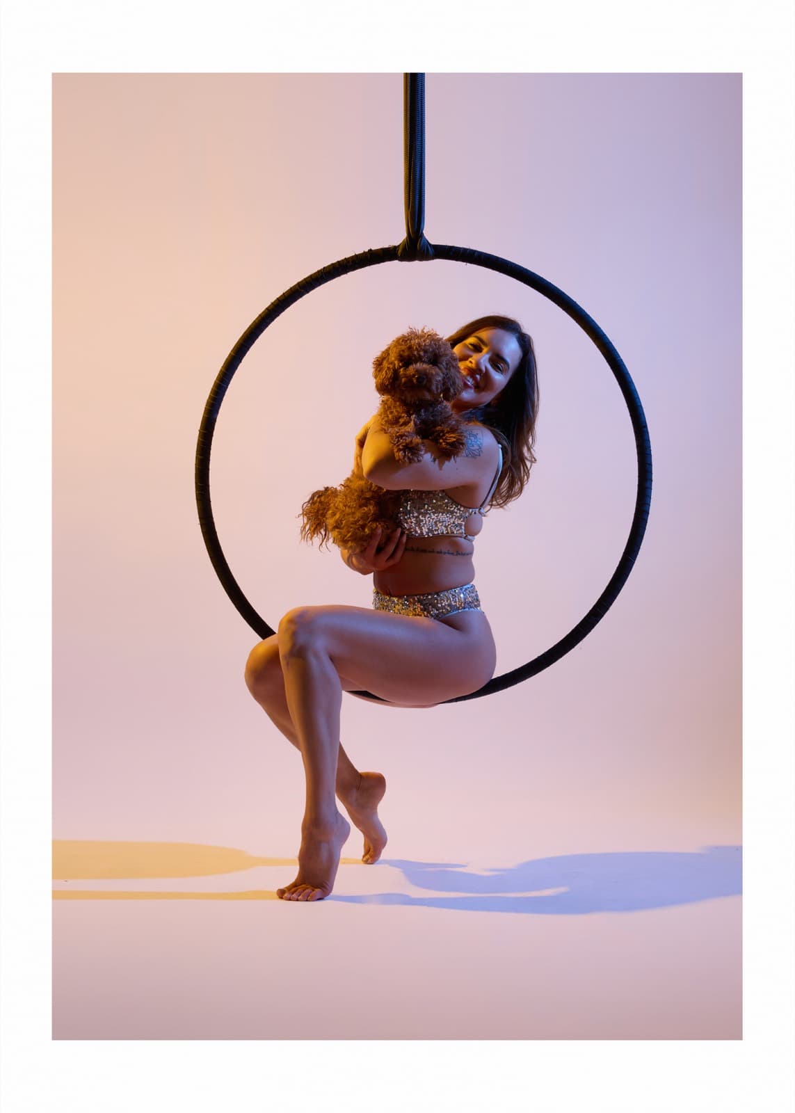Sitting in the aerial hoop with a poodle in her arms